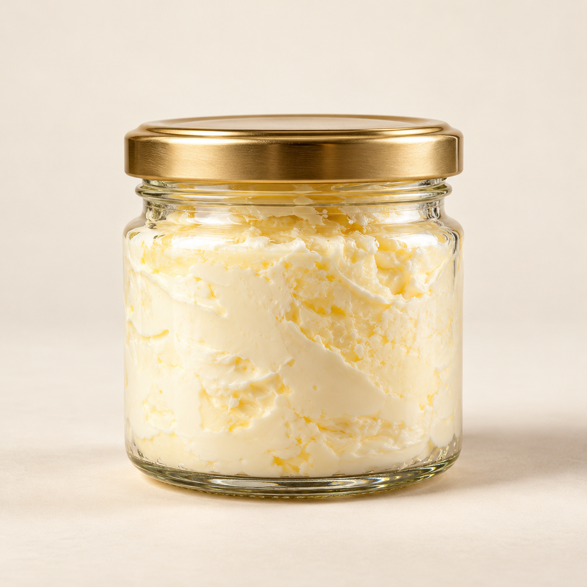 Cream in clear glass jar with brushed gold lid